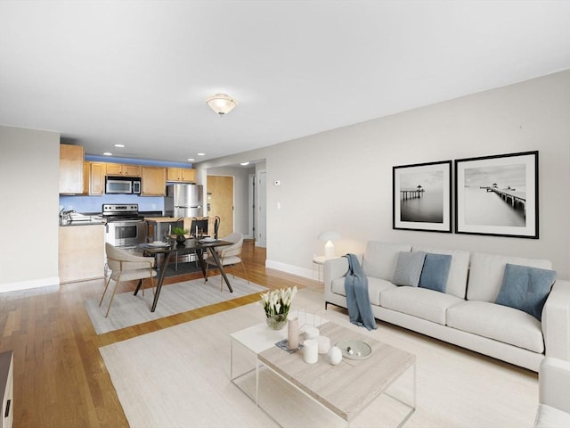 living area featuring recessed lighting, baseboards, and light wood-style floors