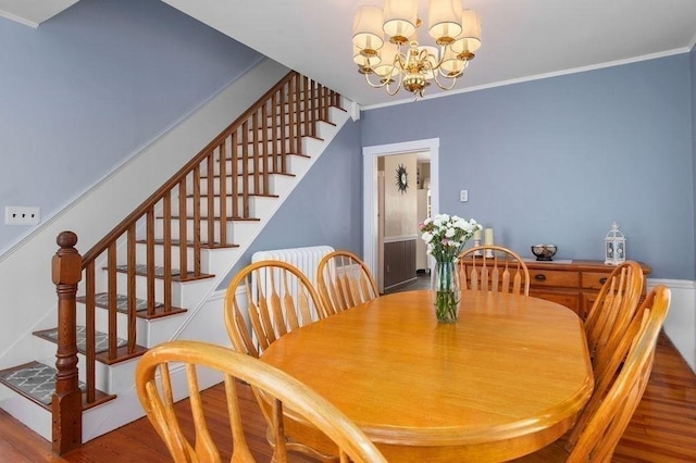 dining area featuring crown molding, an inviting chandelier, stairs, and wood finished floors