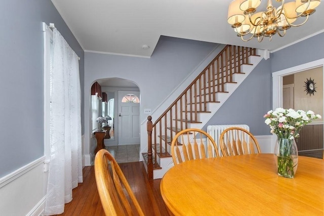 dining area with an inviting chandelier, arched walkways, stairs, baseboards, and wood finished floors