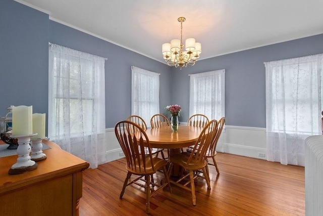 dining area with light wood-style floors, crown molding, a notable chandelier, and a healthy amount of sunlight