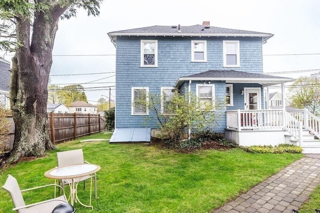 back of property with a lawn, fence, a chimney, and a shingled roof
