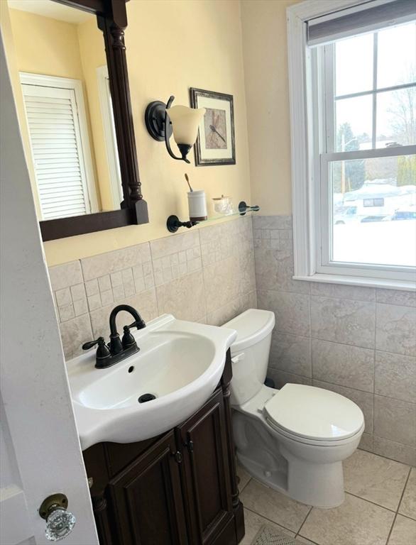 bathroom featuring tile walls, vanity, tile patterned floors, toilet, and a wealth of natural light
