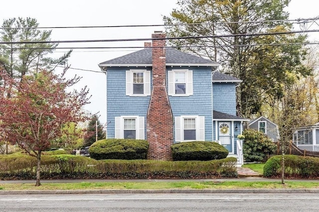 colonial-style house with roof with shingles and a chimney