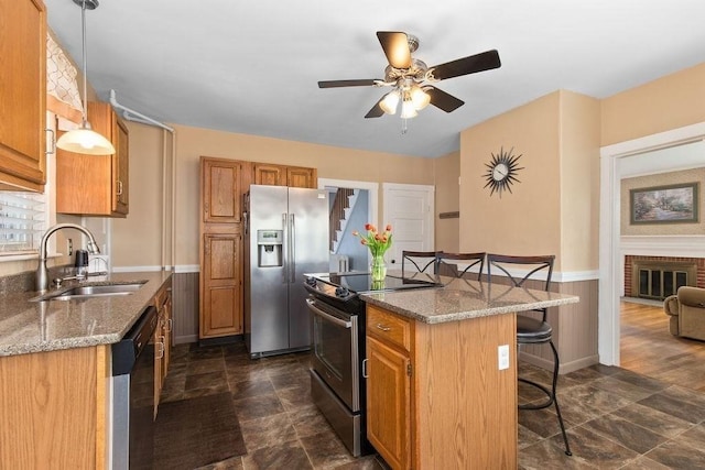 kitchen featuring a breakfast bar area, a ceiling fan, a kitchen island, a sink, and stainless steel appliances