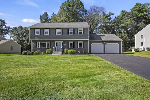 colonial house with aphalt driveway, a front lawn, a chimney, and an attached garage