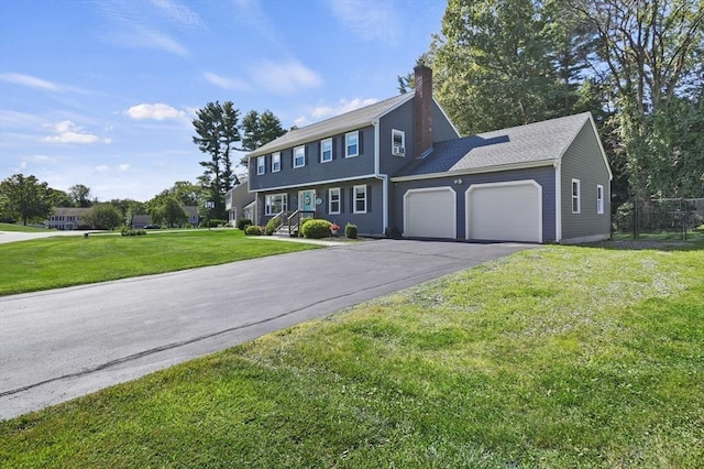 colonial house featuring aphalt driveway, a front yard, a chimney, and an attached garage