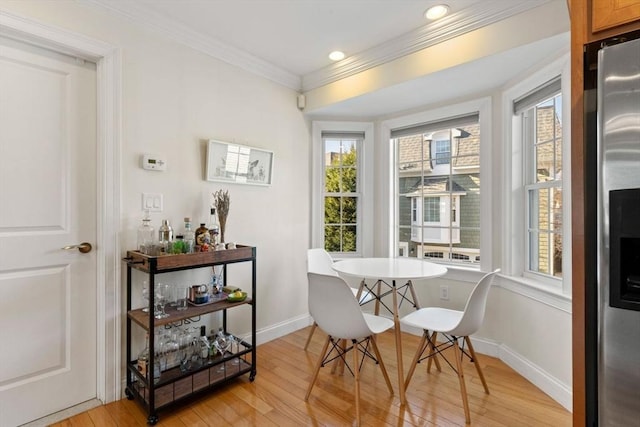 dining area featuring a wealth of natural light, crown molding, and light hardwood / wood-style flooring