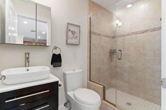 bathroom with toilet, vanity, and a shower with shower door