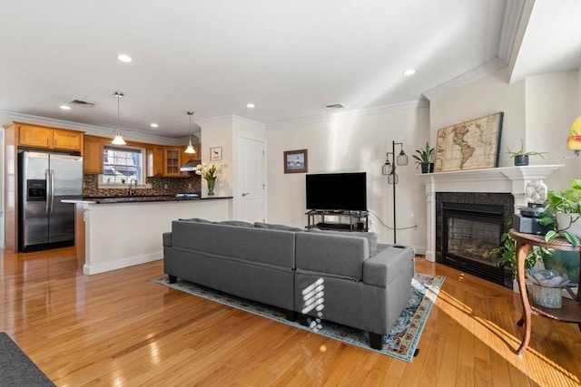 living room featuring light hardwood / wood-style floors, sink, and ornamental molding