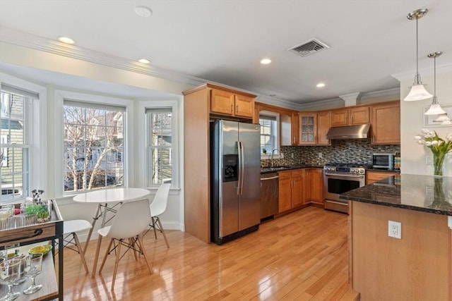 kitchen featuring decorative light fixtures, backsplash, kitchen peninsula, appliances with stainless steel finishes, and dark stone counters