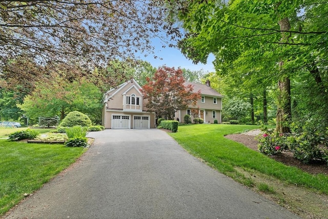 6 Fruit St, Hopkinton, MA 01748 - obstructed view of property with an attached garage, asphalt driveway, a front lawn, and a chimney
