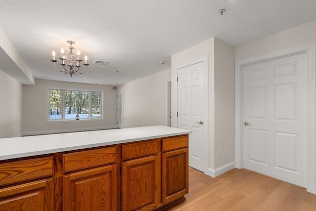 kitchen with light wood-type flooring, brown cabinetry, visible vents, and light countertops