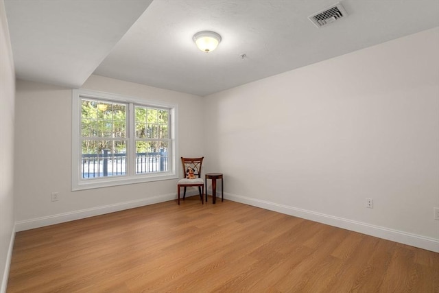 unfurnished room featuring visible vents, light wood-style flooring, and baseboards