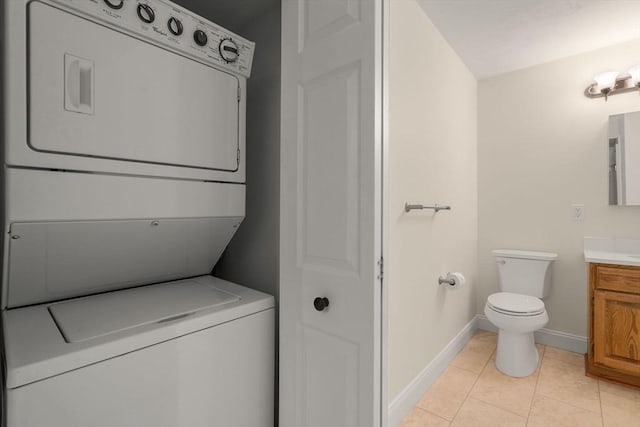 laundry area featuring light tile patterned floors, laundry area, baseboards, and stacked washer / drying machine