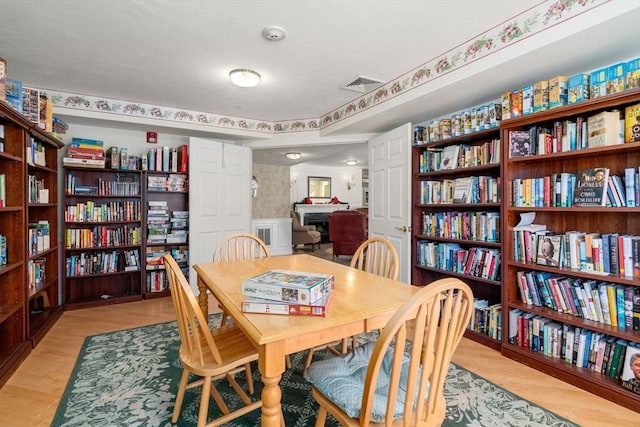 dining area featuring light wood-type flooring, a wainscoted wall, visible vents, and wallpapered walls