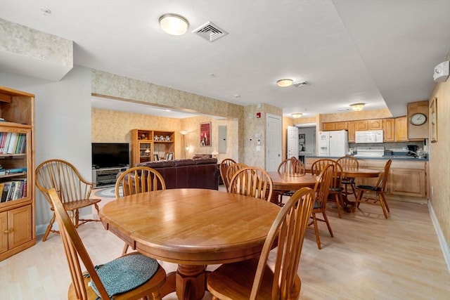 dining area featuring wallpapered walls, electric panel, visible vents, baseboards, and light wood-style flooring