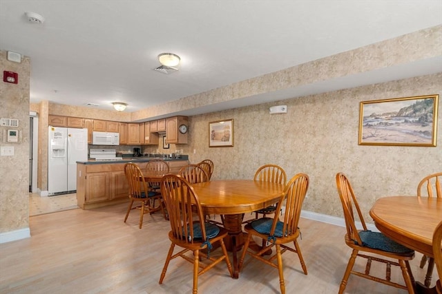 dining area featuring visible vents, wallpapered walls, light wood-style flooring, and baseboards