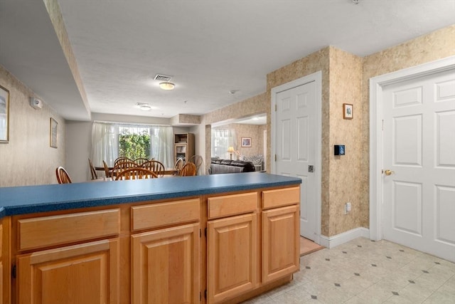 kitchen featuring wallpapered walls, baseboards, visible vents, dark countertops, and open floor plan