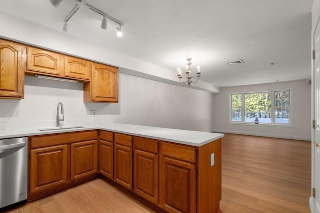 kitchen with brown cabinets, light countertops, a sink, and stainless steel dishwasher