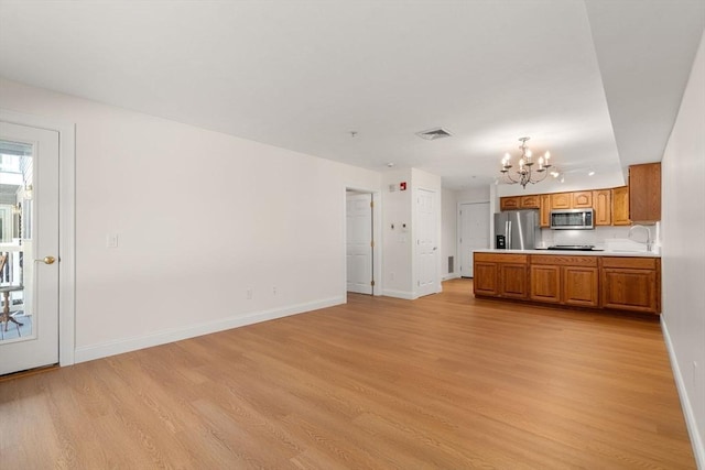 kitchen with visible vents, brown cabinets, open floor plan, stainless steel appliances, and light countertops