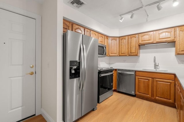 kitchen featuring stainless steel appliances, light countertops, visible vents, light wood-style flooring, and a sink