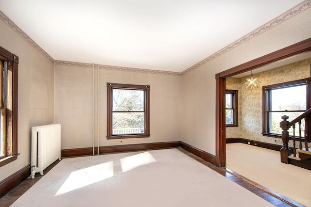 unfurnished room with stairway, wallpapered walls, radiator heating unit, and baseboards