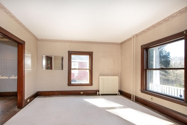 unfurnished room with wallpapered walls, radiator, and baseboards