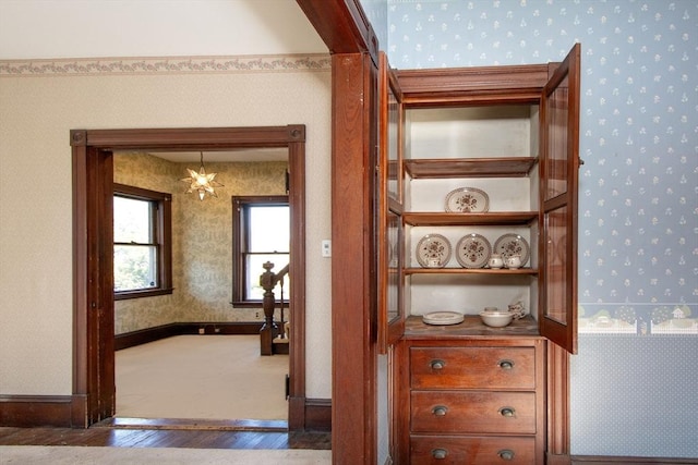 hallway with baseboards, wood finished floors, and wallpapered walls