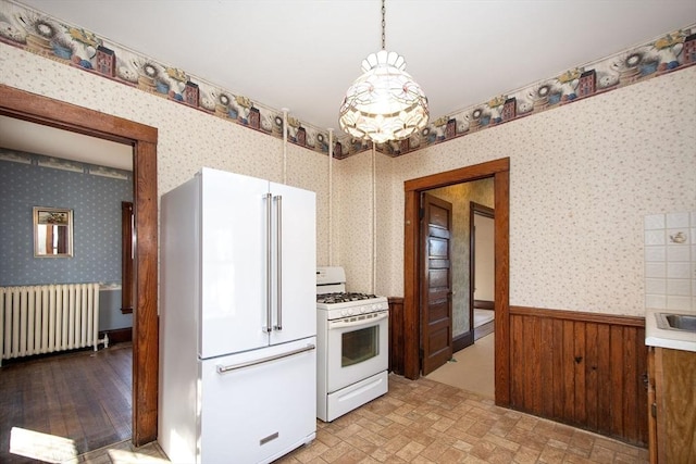 kitchen with brick patterned floor, radiator heating unit, white appliances, wainscoting, and wallpapered walls