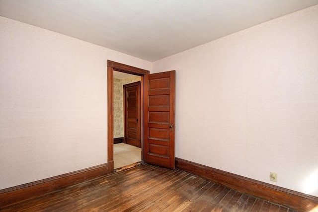 spare room with baseboards and dark wood finished floors