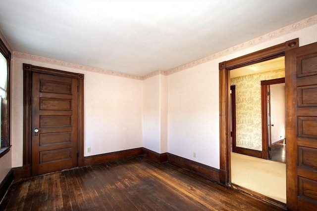 empty room featuring wallpapered walls, baseboards, and wood-type flooring