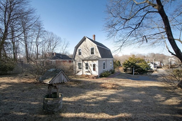 view of front of property with a gambrel roof, entry steps, and a chimney