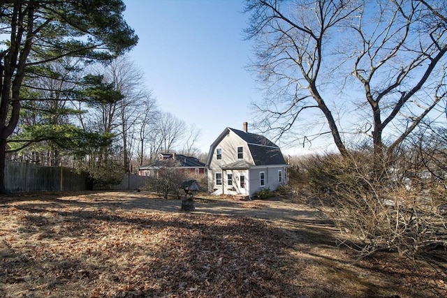 exterior space featuring fence, a gambrel roof, and driveway