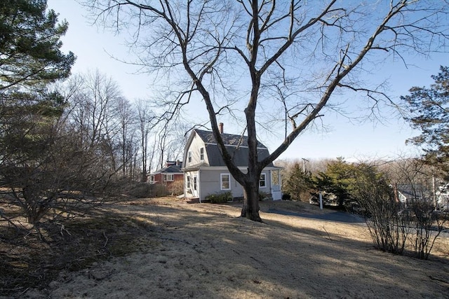 view of property exterior with a gambrel roof and a chimney