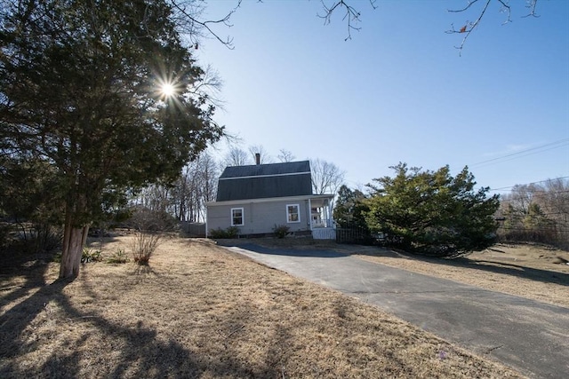 dutch colonial with fence, a gambrel roof, and roof mounted solar panels