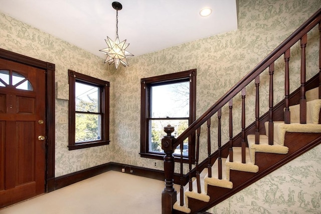 entryway with a notable chandelier, stairway, wallpapered walls, and baseboards