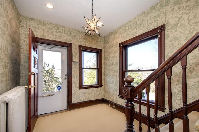 doorway to outside featuring wallpapered walls, radiator, baseboards, and stairs