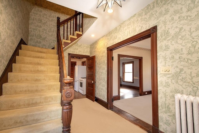 stairway with wallpapered walls, radiator heating unit, wood finished floors, and baseboards