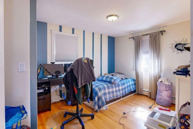 bedroom with wood finished floors and a baseboard radiator