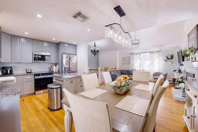 dining room with visible vents, light wood-style flooring, recessed lighting, a fireplace, and a chandelier