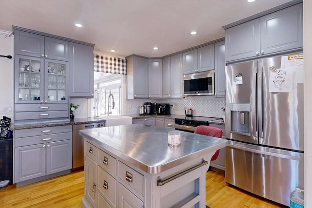 kitchen with stainless steel counters, appliances with stainless steel finishes, light wood-style flooring, and gray cabinetry