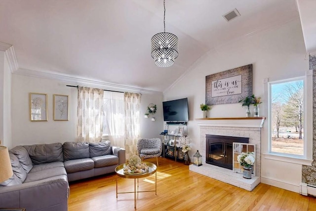 living area featuring crown molding, wood finished floors, visible vents, and a healthy amount of sunlight