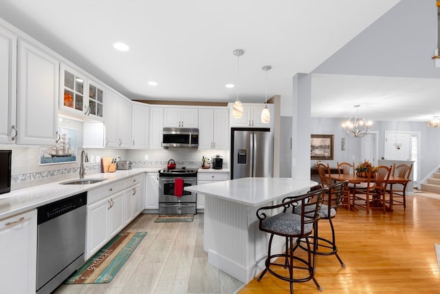 kitchen with appliances with stainless steel finishes, decorative light fixtures, white cabinets, and sink