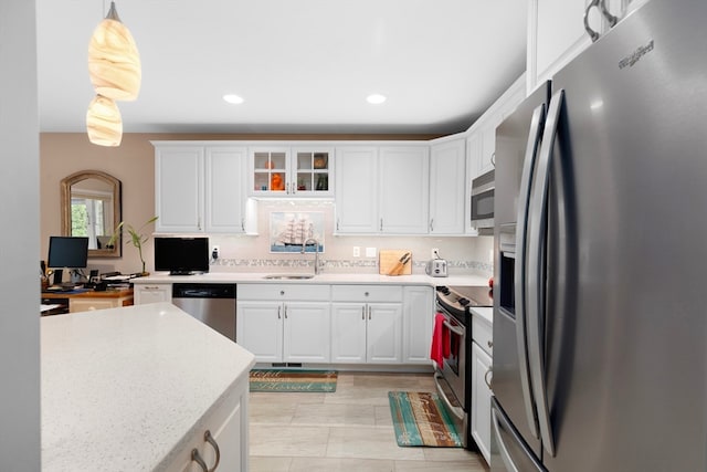 kitchen with appliances with stainless steel finishes, sink, white cabinetry, pendant lighting, and decorative backsplash