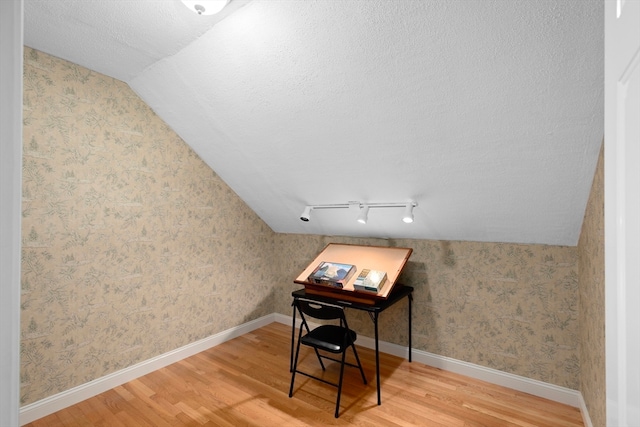 office area with hardwood / wood-style flooring, a textured ceiling, and vaulted ceiling