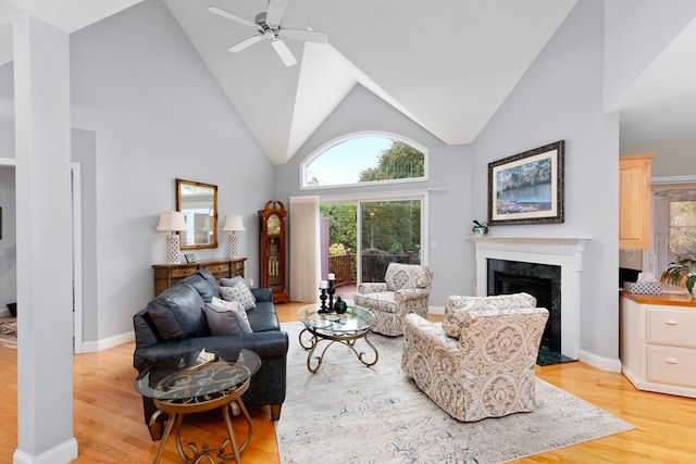 living room with ceiling fan, high vaulted ceiling, light wood-type flooring, and a fireplace