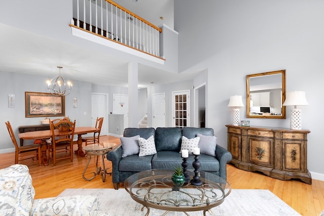 living room featuring light hardwood / wood-style flooring, a chandelier, and a high ceiling