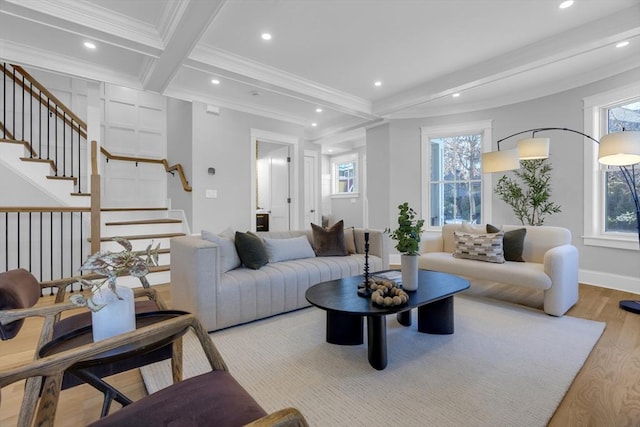 living room featuring a healthy amount of sunlight, ornamental molding, light hardwood / wood-style floors, and beam ceiling