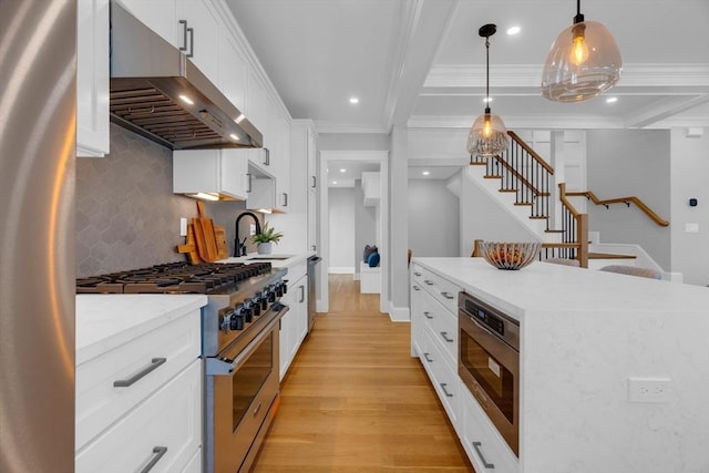 kitchen with white cabinets, decorative light fixtures, stainless steel appliances, ornamental molding, and range hood