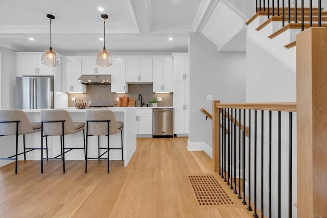 kitchen with tasteful backsplash, pendant lighting, sink, stainless steel appliances, and white cabinets